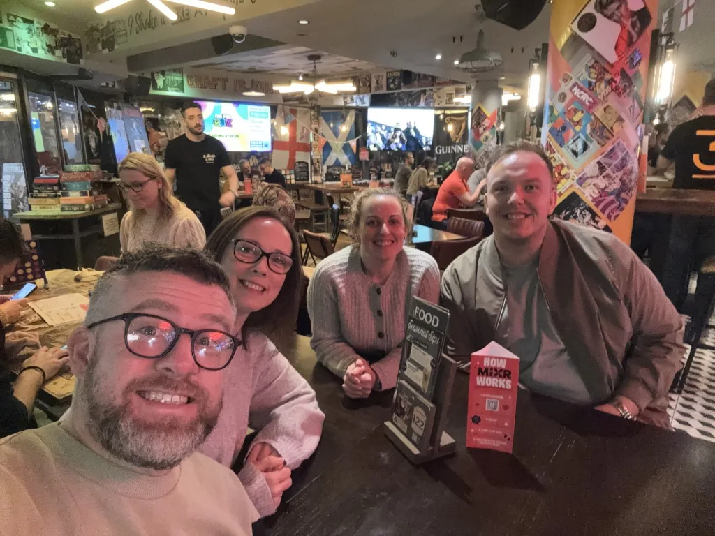 A group of quiz teammates gathered around a table with drinks