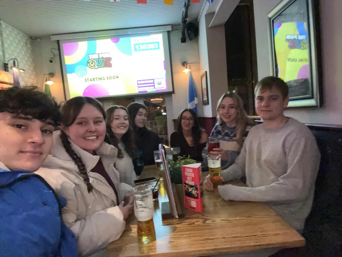 A large quiz team gathered around a table in a busy pub