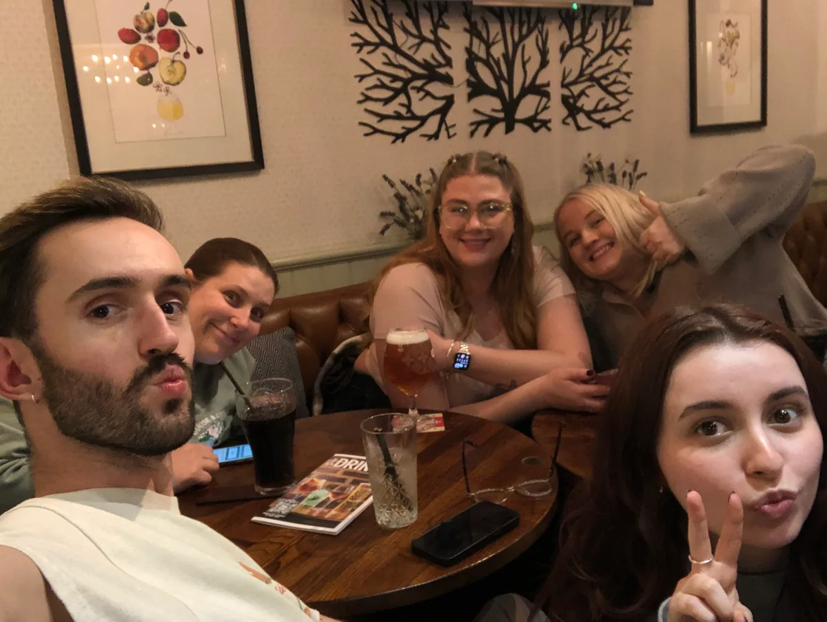 Five quiz teammates sitting together around a pub table