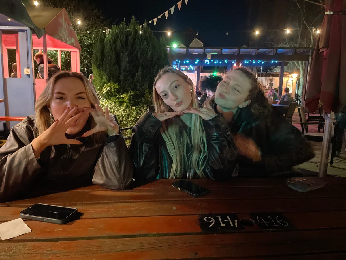 Three teammates enjoying an outdoor pub evening under string lights