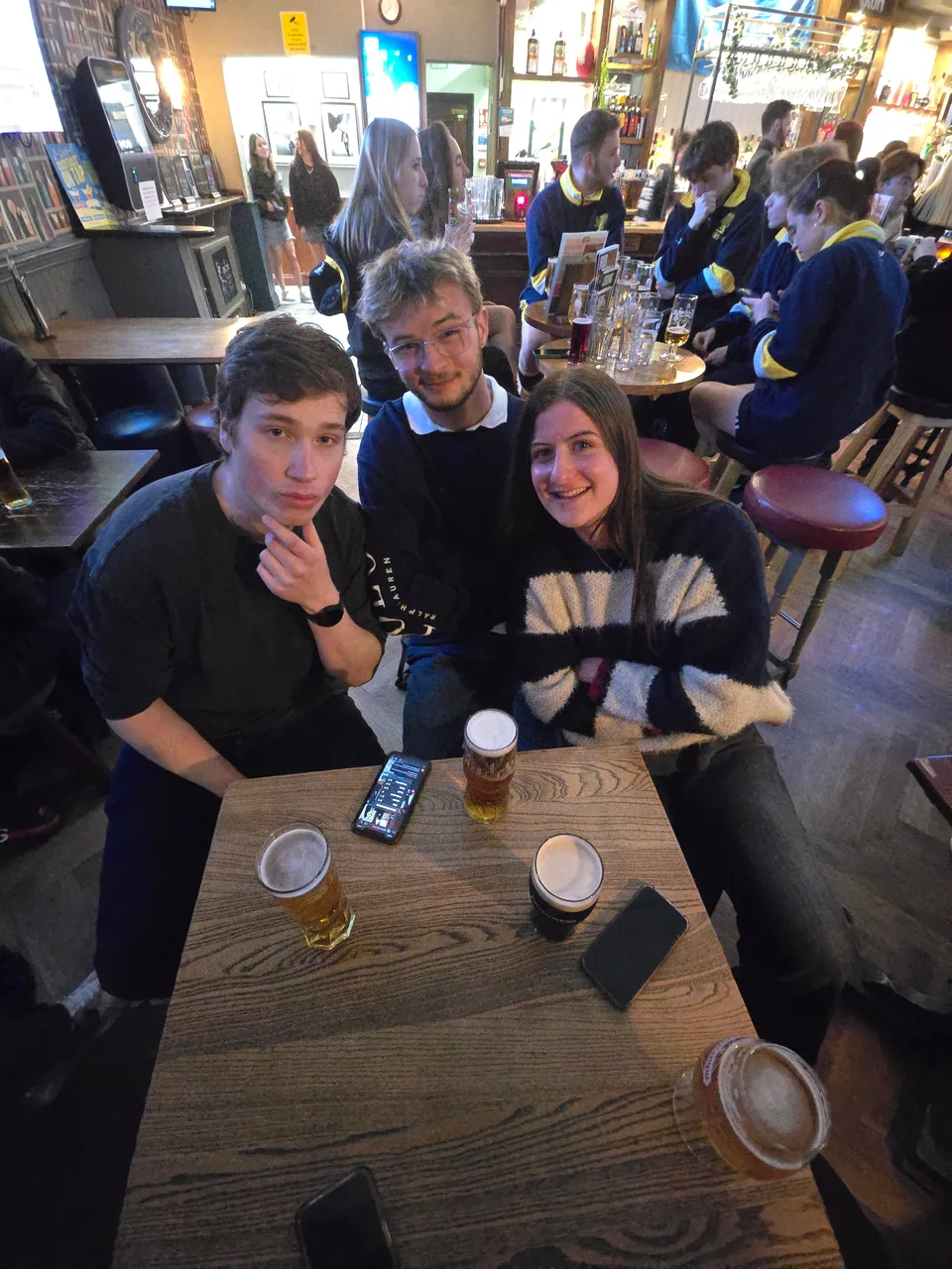 Three quiz teammates seated around a table in a spacious pub