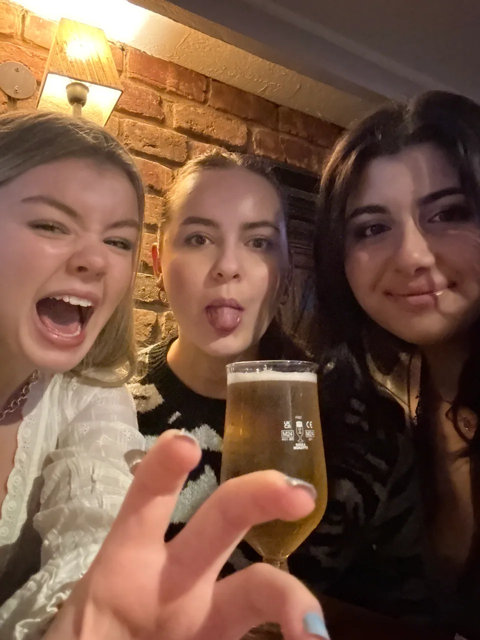 Three teammates sharing a quiz night with drinks and a phone
