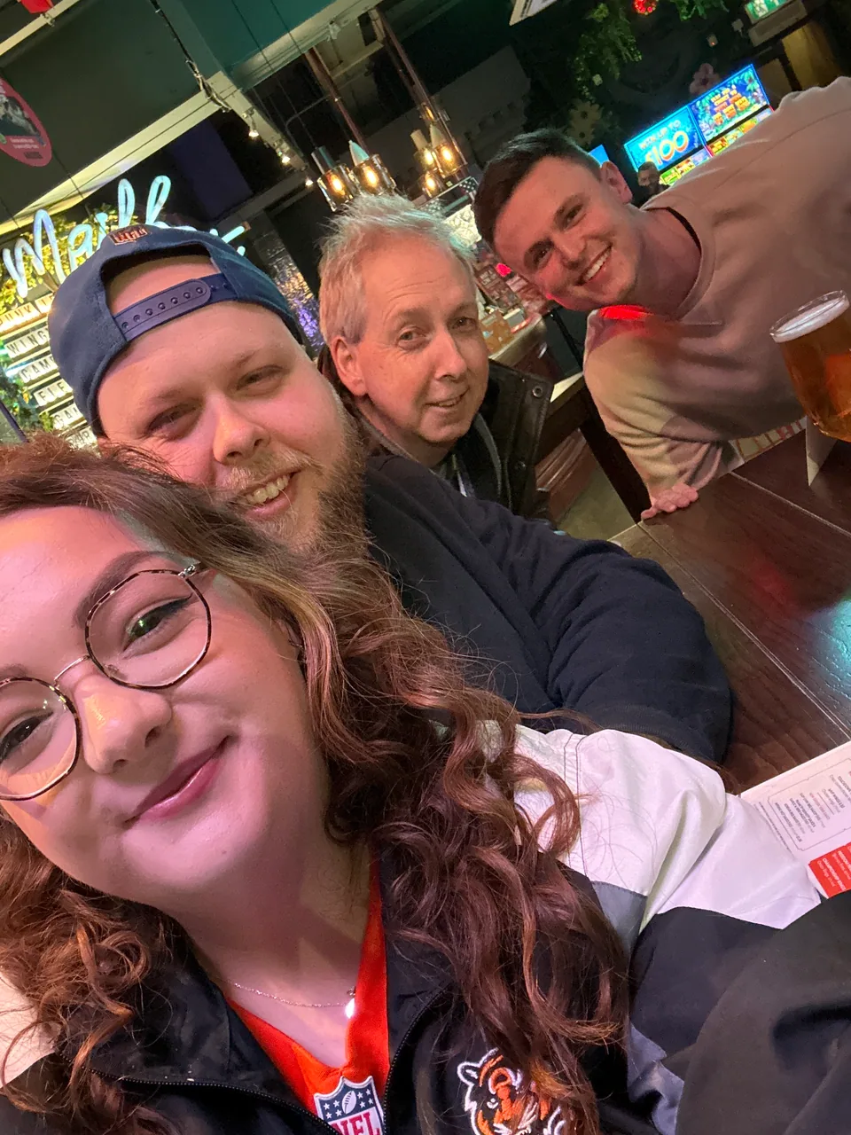 Four smiling quiz teammates gathered around a pub table