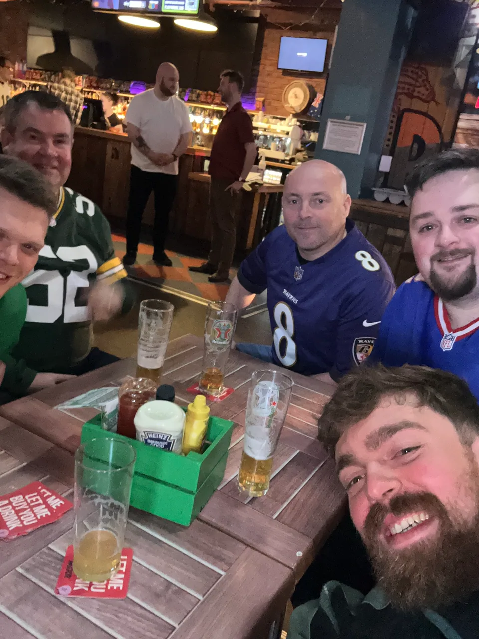 A group of six teammates gathered around a pub table