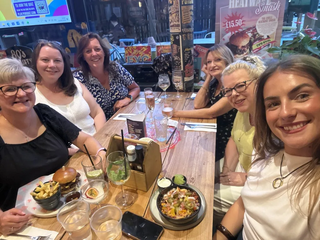 Six teammates smiling around a long pub table