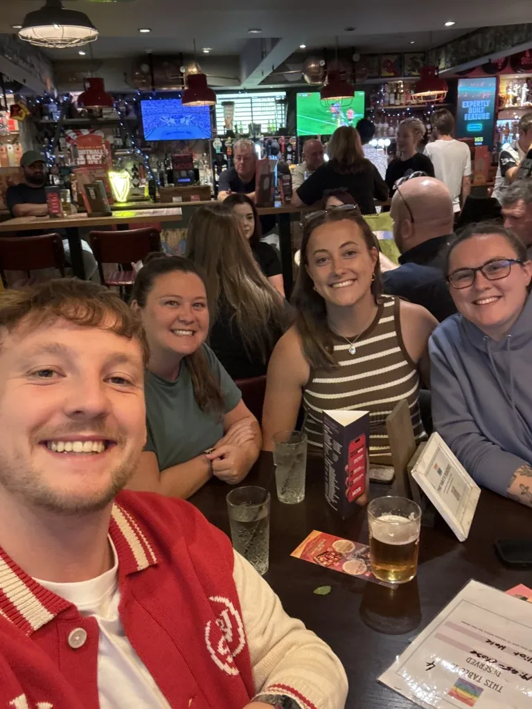 Four smiling teammates sitting together in a pub